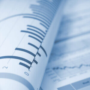 Rolled financial documents with visible bar charts and line graphs in blue tones, showing numerical data and trends.