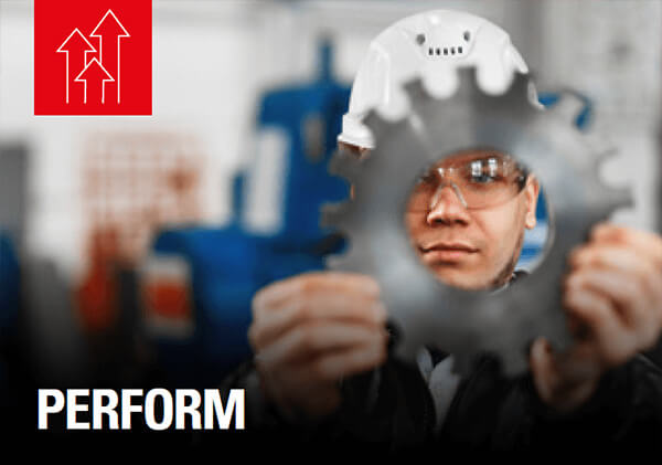 Worker in safety glasses and white hard hat holds a large metal gear; "PERFORM" below, red upward arrows icon at top left.