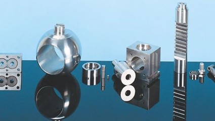 Precision-engineered metal parts, including gears and cylinders, displayed on a reflective black surface with a blue background.