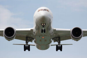 Front view of a large commercial aeroplane approaching to land with landing gear deployed and both engines visible against a clear sky.